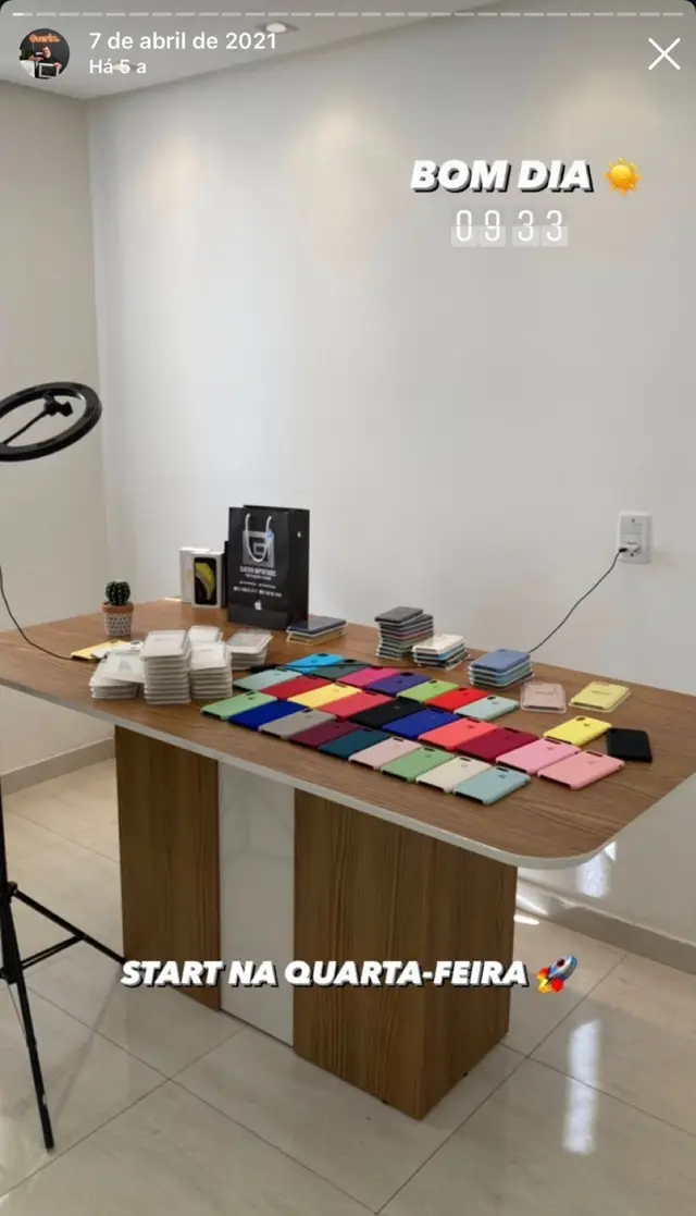 Primeira sede da Guerin no apartamento, em 7 de abril de 2021: mesa com iPhones e dezenas de capinhas coloridas alinhadas, ao lado de um ring light