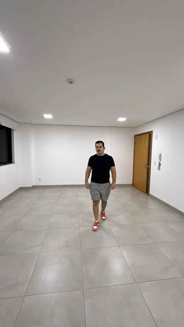 Kevin caminhando no novo escritório comercial da Guerin, um amplo salão vazio com piso claro, recém-inaugurado